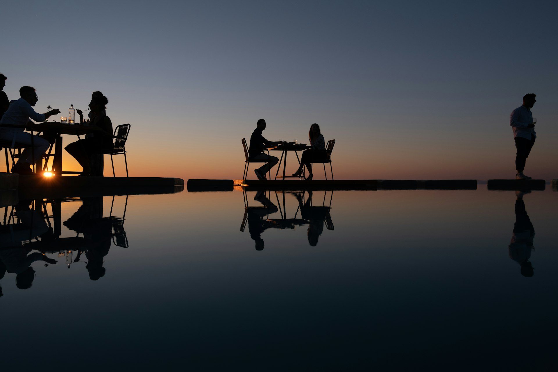 Two silhouettes at the pool's edge at dusk