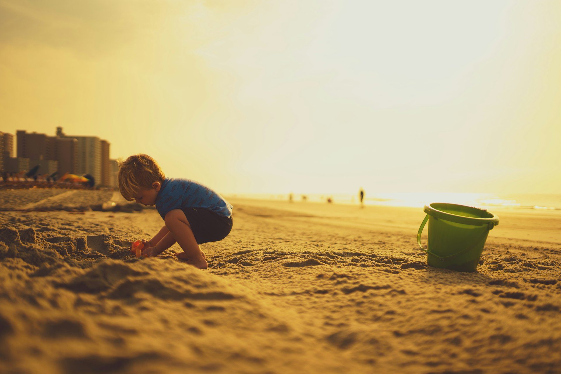 A boy building sandcastles in golden light